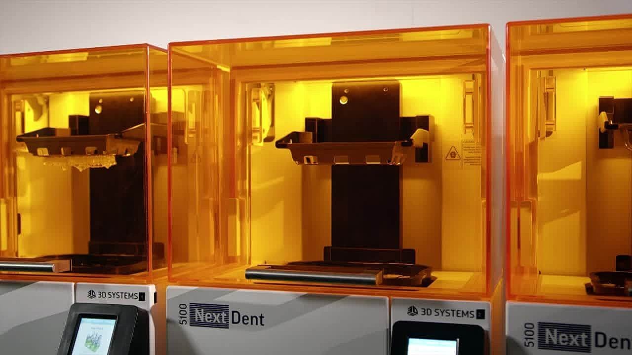 3D printers in bright orange enclosures.