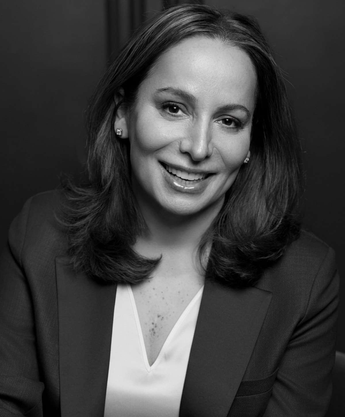 Woman smiling in professional attire, black and white.
